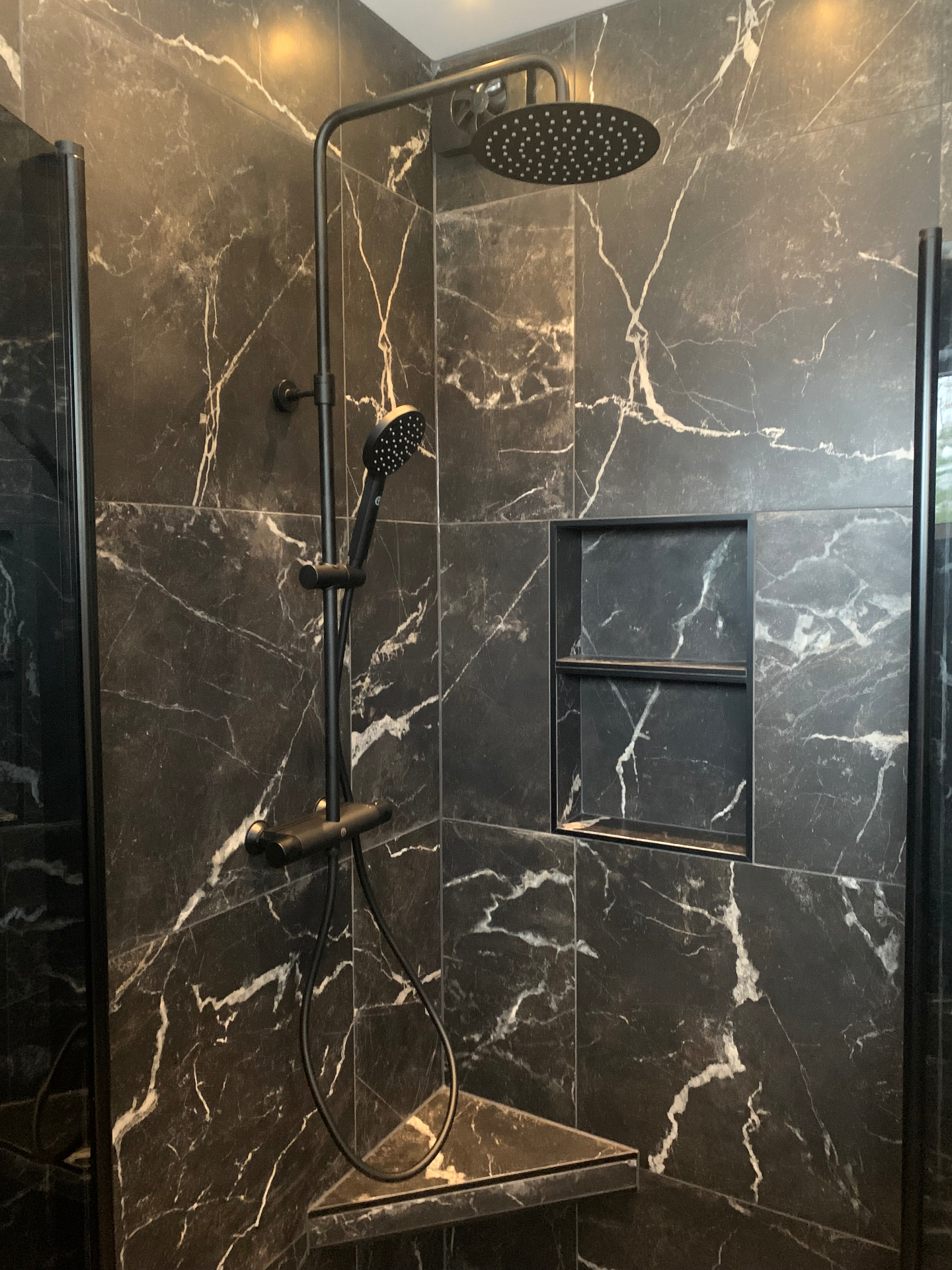 Färdigt badrum efter totalrenovering i Säffle med mörk plattsättning, takdusch och vägghängd WC